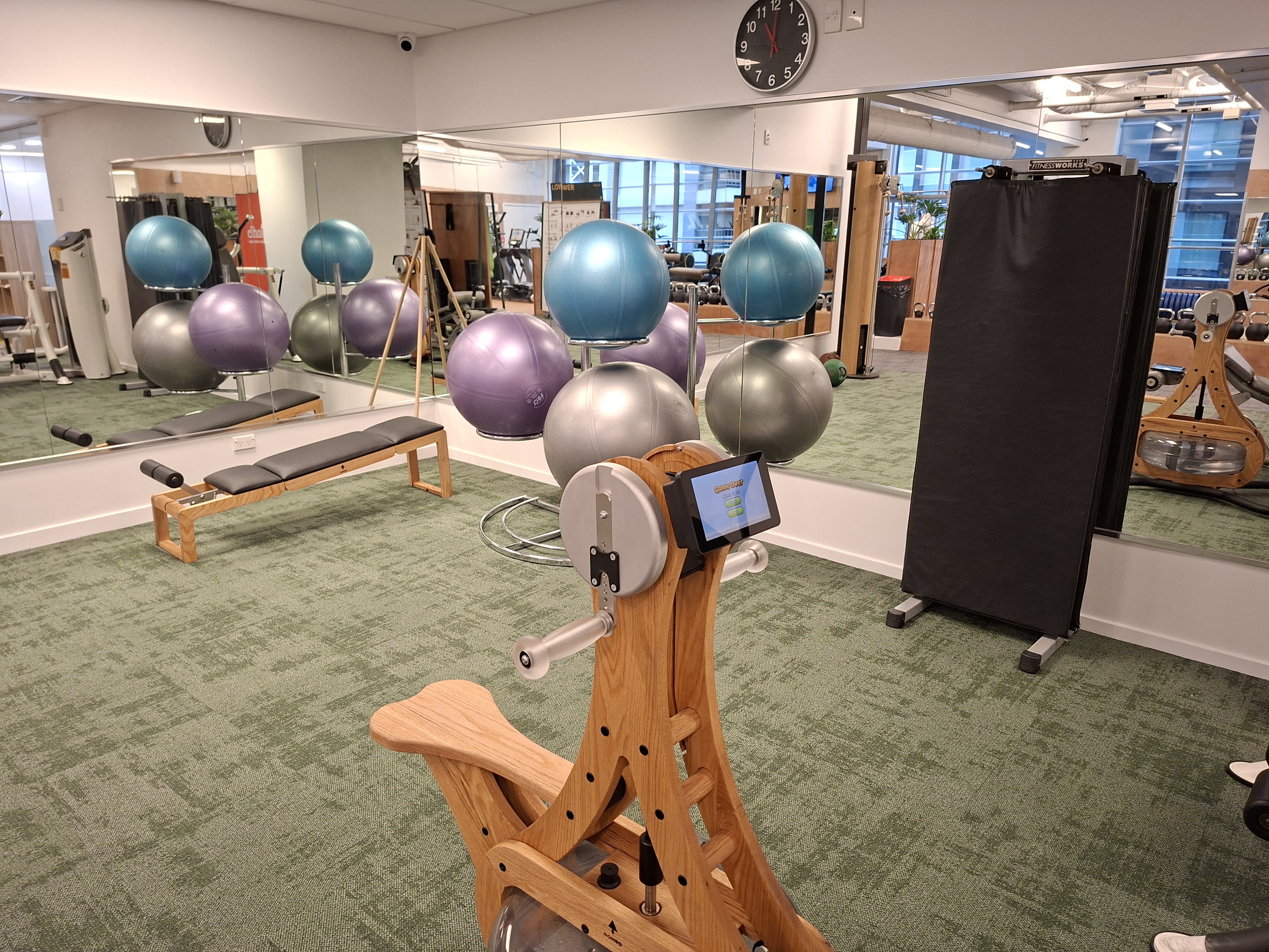 Core zone — timber ab machine, Swiss balls, flat bench and mirrors reflecting the training floor