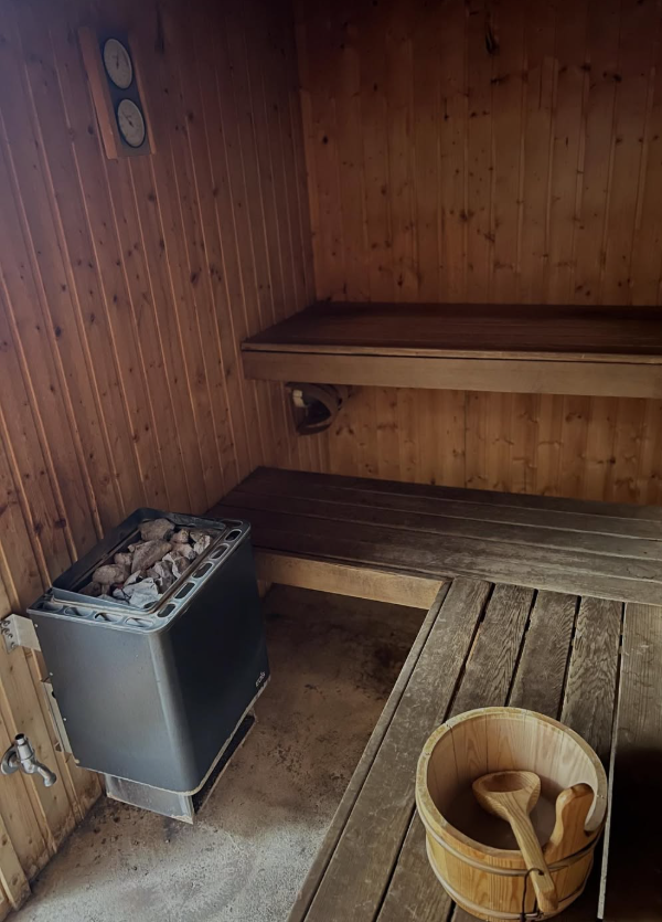 Tortoise sauna interior — timber benches, electric heater and ladle bucket